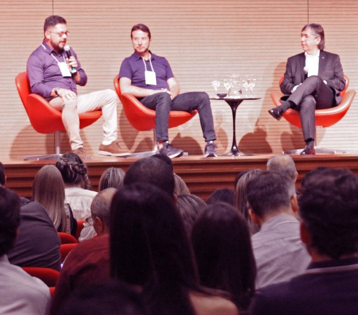 Debate entre executivos no palco, visto do fundo da plateia